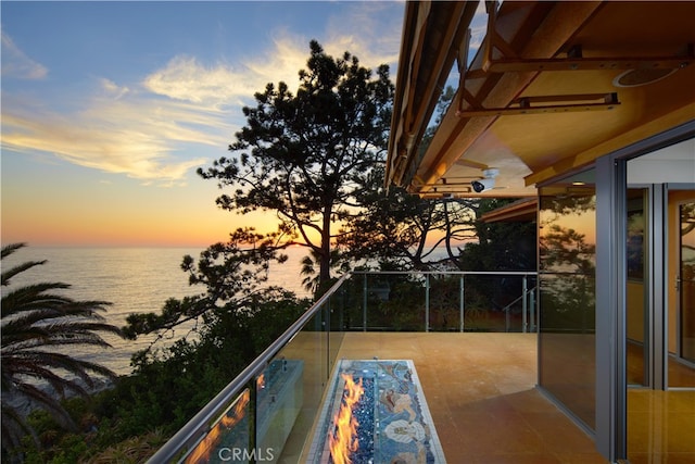 balcony at dusk featuring a water view