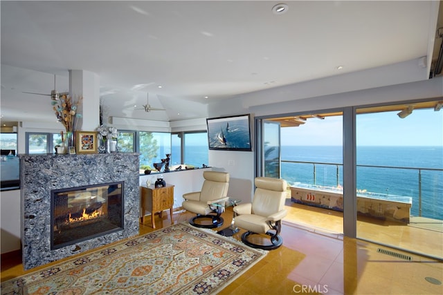 living room with a premium fireplace, a water view, and light tile patterned flooring