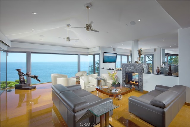 living room with ceiling fan, lofted ceiling, a premium fireplace, and a water view