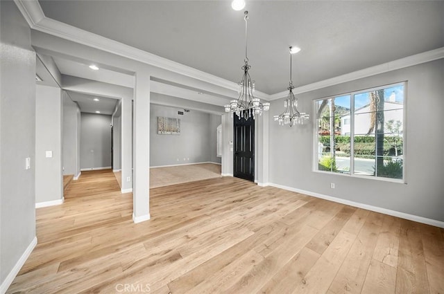 unfurnished dining area featuring light wood-type flooring, crown molding, and a chandelier