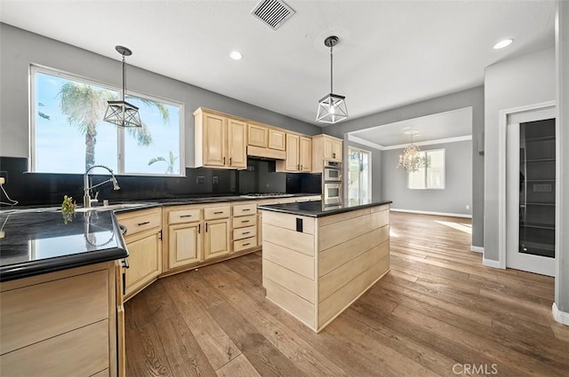 kitchen featuring pendant lighting, a kitchen island, sink, and tasteful backsplash