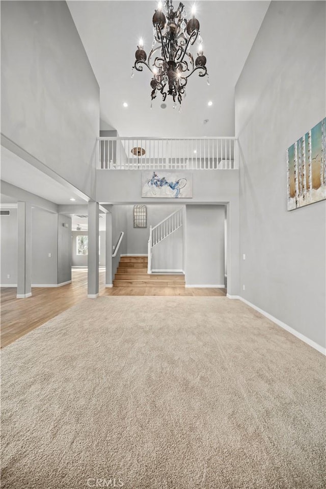 unfurnished living room with carpet flooring, a high ceiling, and an inviting chandelier