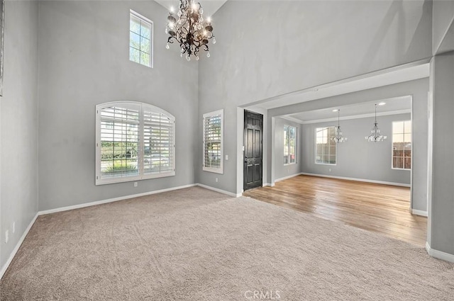 unfurnished living room featuring light colored carpet, a chandelier, and a high ceiling