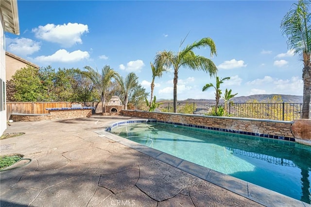 view of pool featuring a mountain view, exterior fireplace, and a patio area