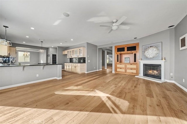 unfurnished living room with ceiling fan, sink, and light hardwood / wood-style flooring