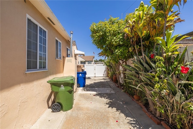 view of side of property with a patio area, fence, and stucco siding