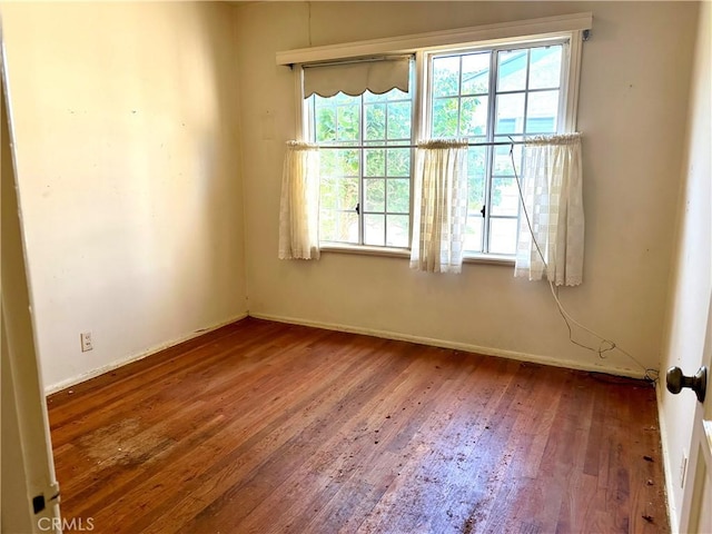 unfurnished room featuring baseboards and wood finished floors