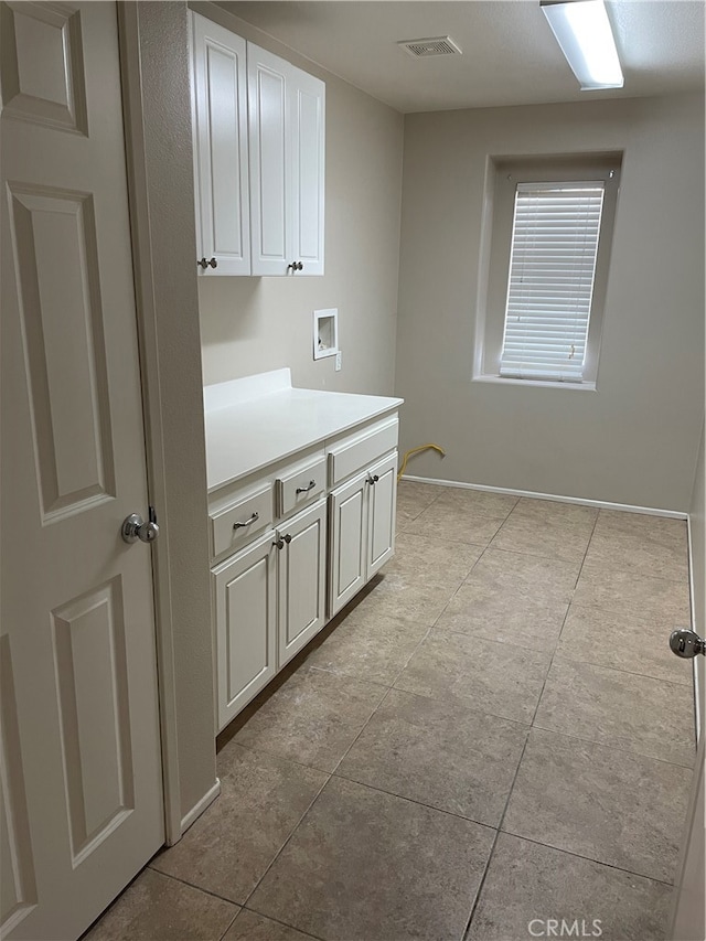 clothes washing area featuring hookup for a washing machine, light tile patterned floors, and cabinets