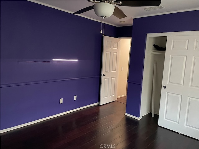 unfurnished bedroom featuring dark wood-type flooring, crown molding, a closet, and ceiling fan