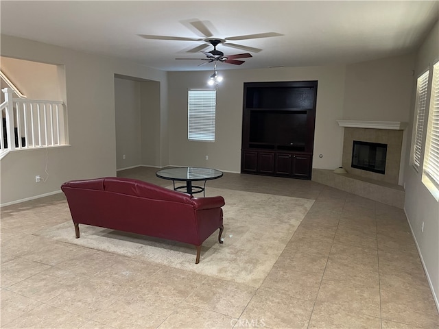 tiled living room with ceiling fan and a tile fireplace