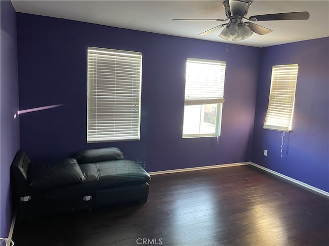 living area with ceiling fan and dark hardwood / wood-style flooring