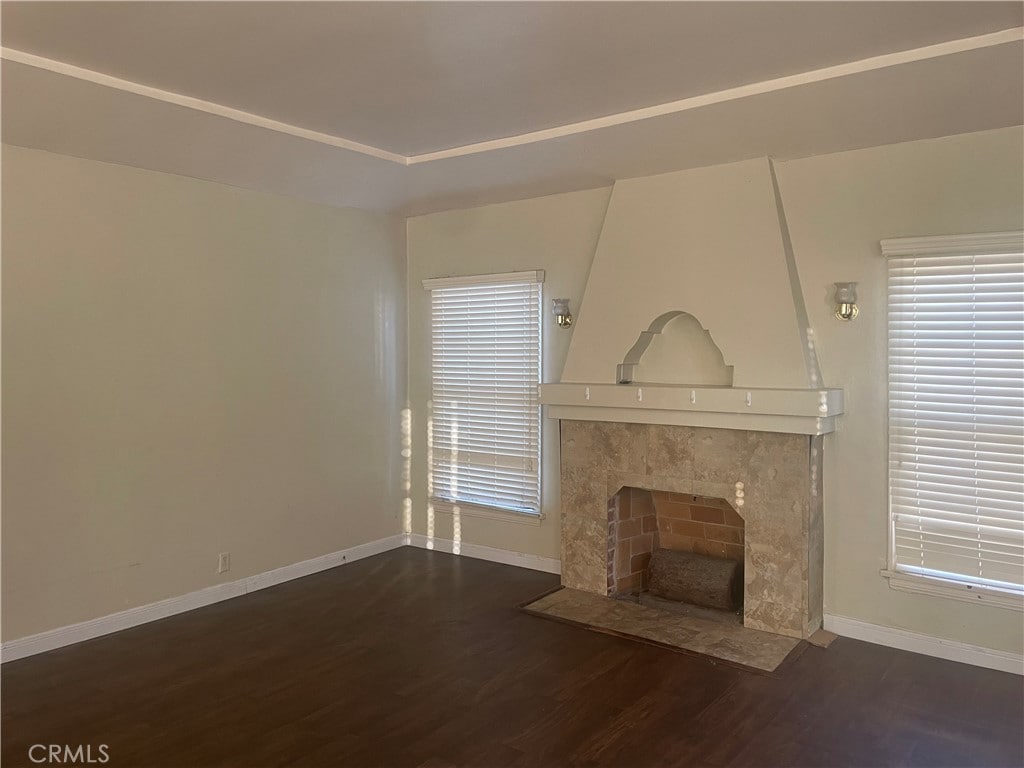 unfurnished living room featuring a tiled fireplace and dark hardwood / wood-style floors