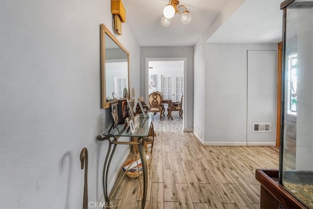 corridor featuring a notable chandelier and light wood-type flooring