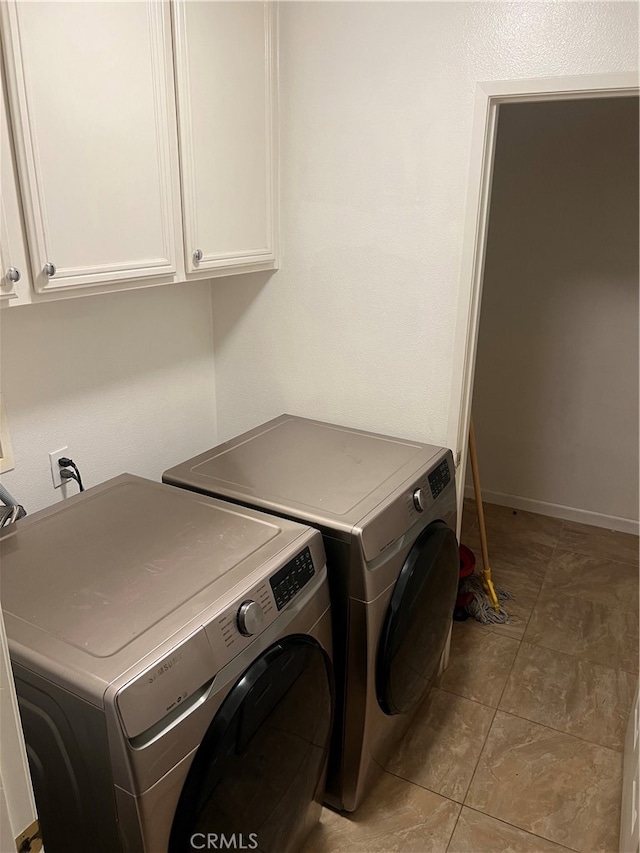 washroom with washing machine and clothes dryer, light tile patterned floors, and cabinets