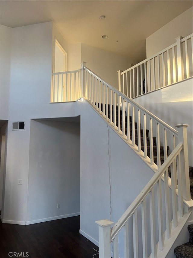 staircase featuring a high ceiling and wood-type flooring