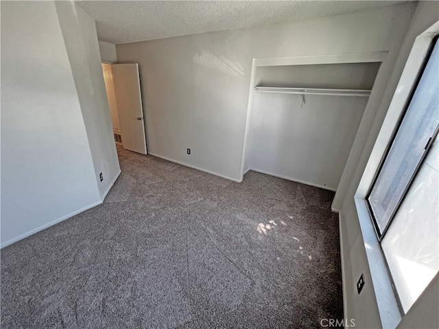 unfurnished bedroom featuring a textured ceiling, carpet flooring, and a closet