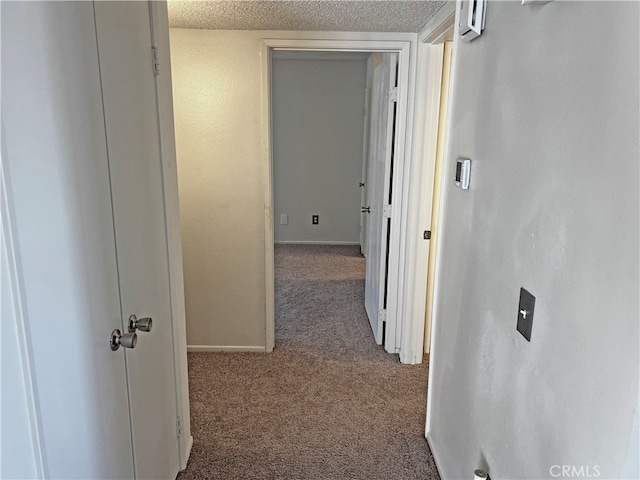 hall with a textured ceiling and carpet flooring