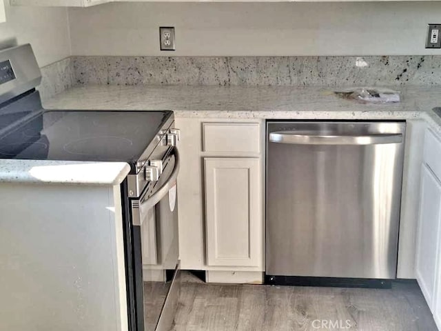 kitchen with white cabinetry, appliances with stainless steel finishes, dark hardwood / wood-style floors, and light stone counters