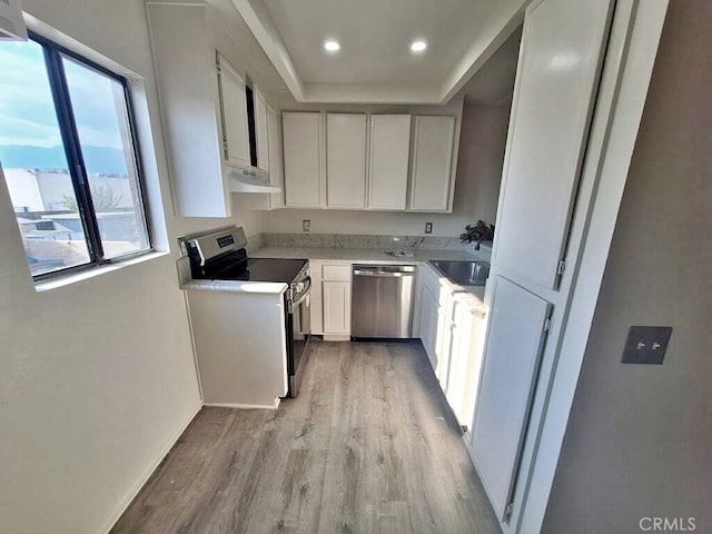 kitchen with appliances with stainless steel finishes, light hardwood / wood-style floors, sink, and white cabinets