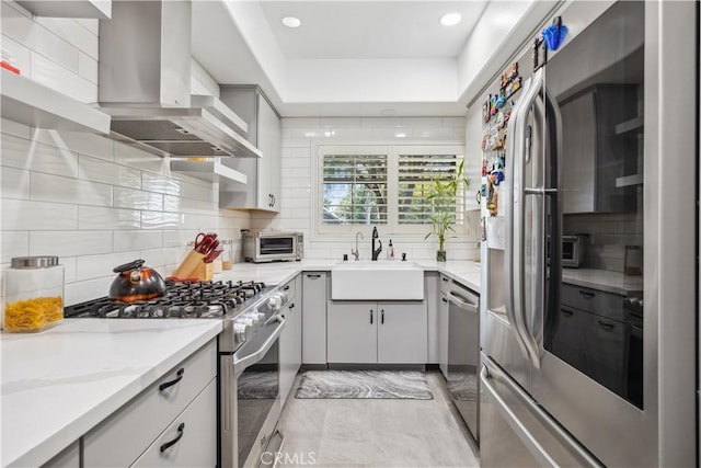 kitchen with sink, exhaust hood, light stone counters, stainless steel appliances, and backsplash