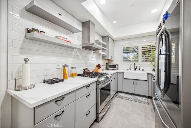 kitchen featuring sink, extractor fan, gray cabinetry, tasteful backsplash, and appliances with stainless steel finishes