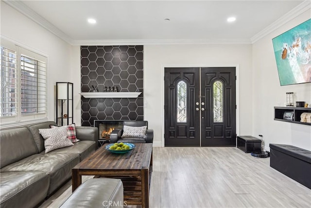 living room with ornamental molding, a fireplace, and light wood-type flooring