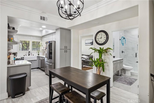 dining area with an inviting chandelier, sink, and ornamental molding