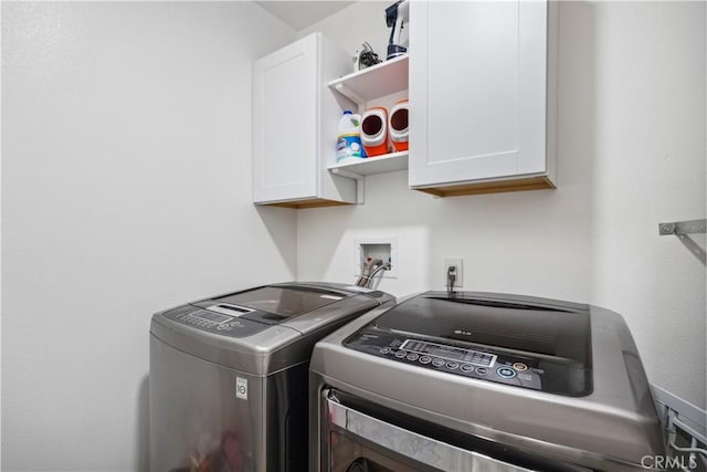 clothes washing area with cabinets and washing machine and clothes dryer