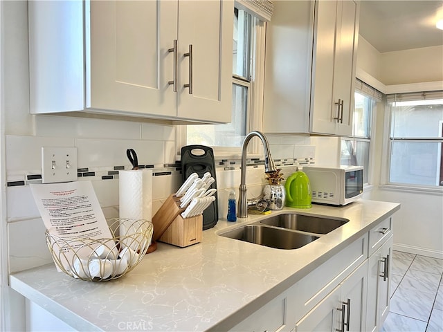 kitchen featuring tasteful backsplash, light stone counters, and sink