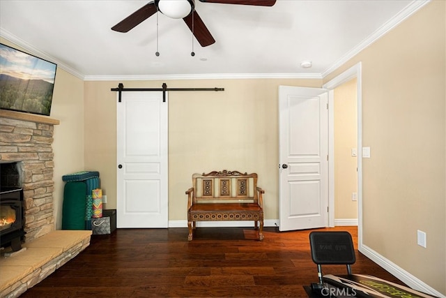 sitting room featuring crown molding, dark hardwood / wood-style floors, ceiling fan, and a wood stove