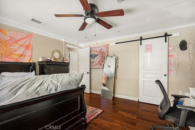 bedroom with ceiling fan, a barn door, dark hardwood / wood-style floors, and ornamental molding