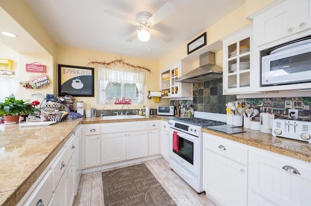 kitchen with light hardwood / wood-style floors, sink, white cabinetry, wall chimney range hood, and white appliances