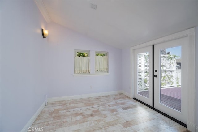 spare room featuring light hardwood / wood-style flooring, vaulted ceiling, and french doors