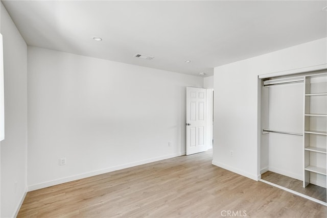 unfurnished bedroom with light hardwood / wood-style flooring and a closet