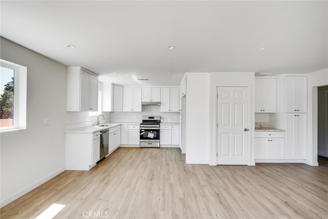 kitchen featuring white cabinets, appliances with stainless steel finishes, light wood-type flooring, and sink