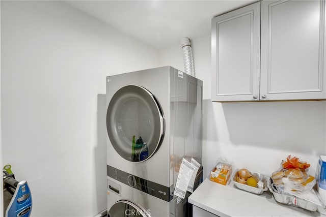 washroom featuring stacked washer / dryer and cabinets