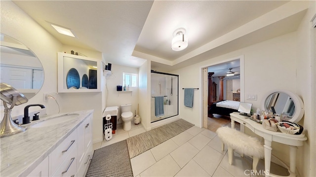 bathroom with vanity, tile patterned flooring, a tray ceiling, toilet, and a shower with door