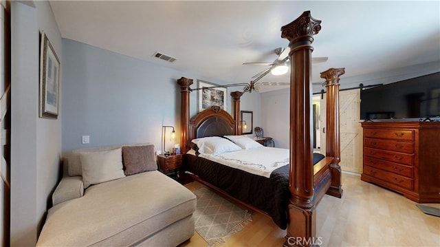 bedroom featuring light hardwood / wood-style flooring, ceiling fan, and a barn door