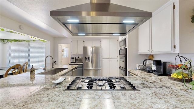 kitchen with white cabinets, stainless steel appliances, light stone countertops, and range hood