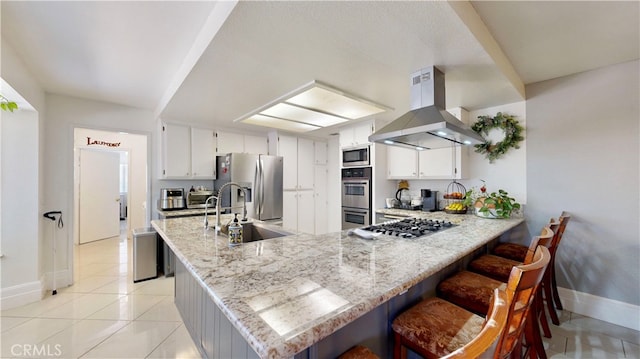 kitchen with appliances with stainless steel finishes, white cabinets, island range hood, kitchen peninsula, and sink