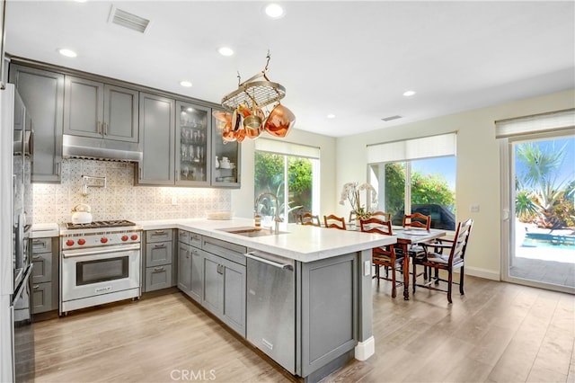 kitchen featuring gray cabinetry, appliances with stainless steel finishes, sink, light wood-type flooring, and kitchen peninsula