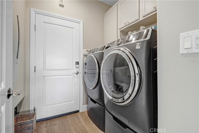 washroom with cabinets, washing machine and dryer, and light hardwood / wood-style floors