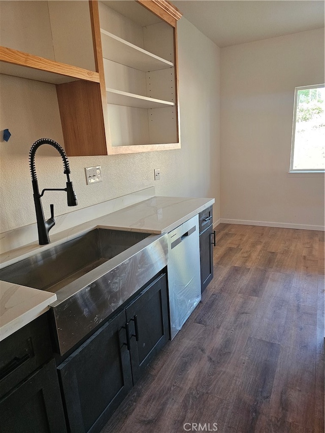 kitchen featuring dark hardwood / wood-style floors, light stone countertops, dishwasher, and sink