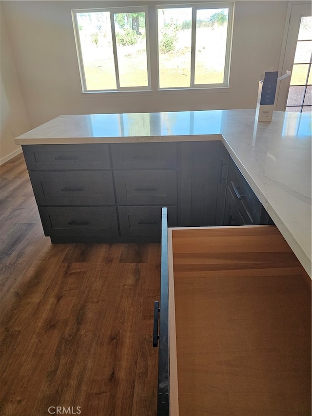 kitchen featuring light stone counters, plenty of natural light, and dark hardwood / wood-style floors