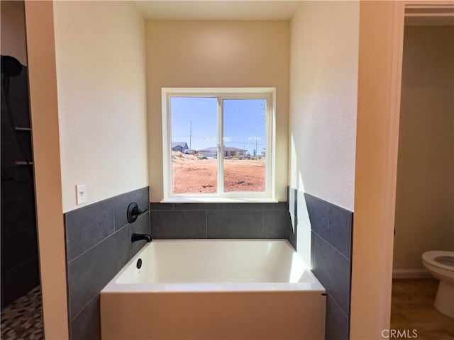 bathroom featuring a tub to relax in, tile walls, and toilet