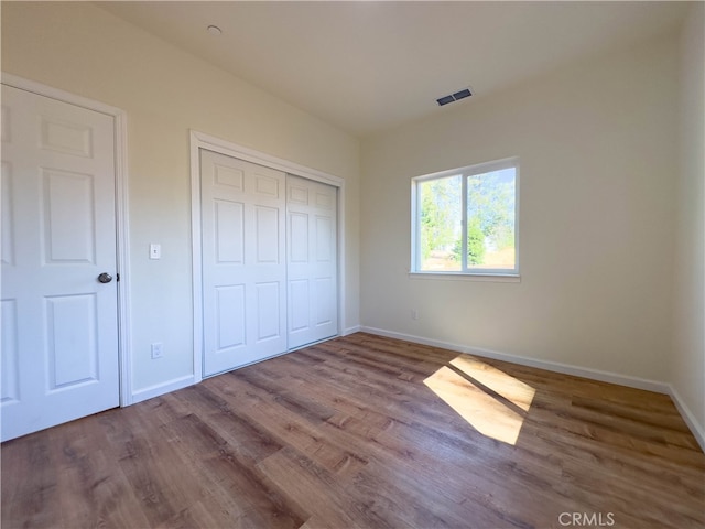 unfurnished bedroom with a closet and hardwood / wood-style flooring