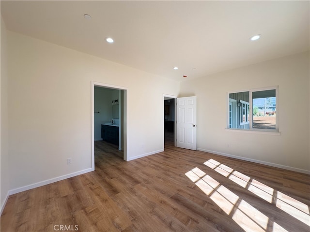 unfurnished bedroom with connected bathroom and hardwood / wood-style flooring