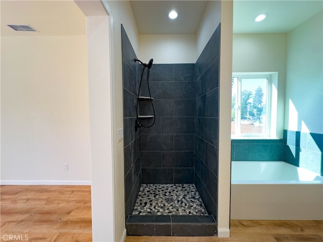 bathroom featuring plus walk in shower and hardwood / wood-style floors