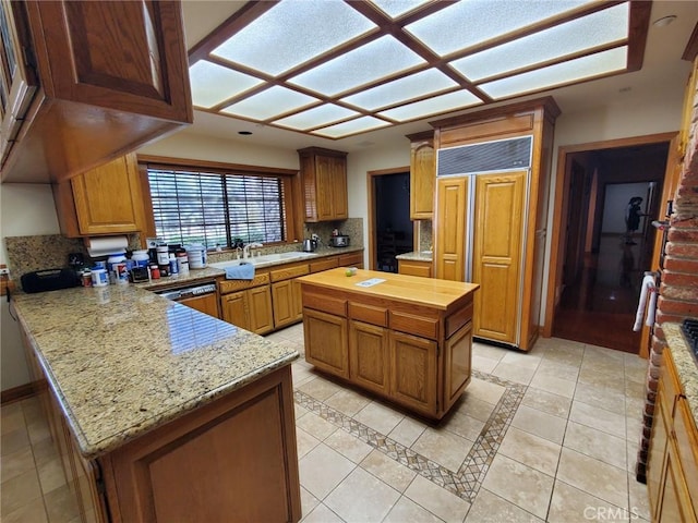 kitchen featuring decorative backsplash, paneled built in fridge, a kitchen island, and light tile patterned floors