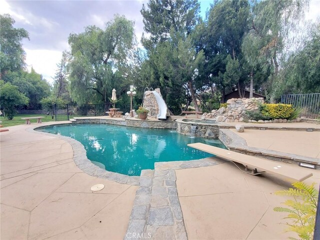 view of pool with a patio area, an in ground hot tub, and a water slide